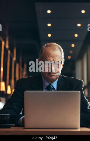 Senior Geschäftsmann Arbeiten am Laptop während im Cafe sitzen. Reifen kaukasischen Mann in Anzug im Cafe sitzen Arbeiten am Laptop. Stockfoto