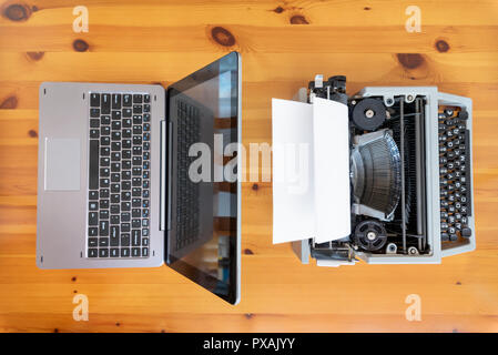 Alte Schreibmaschine vs neue Laptop auf dem Tisch. Konzept der Technologie Fortschritt. Stockfoto