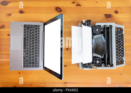 Alte Schreibmaschine vs neue Laptop auf dem Tisch. Konzept der Technologie Fortschritt. Stockfoto
