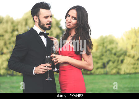 Glückliches Paar Liebhaber mit einem Glas Wein oder Champagner stehen draußen im Garten während der hochzeitsfeier oder Bankett Stockfoto