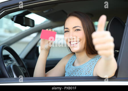 Gerne Fahrer mit einer leeren Karte oder Lizenz mit Daumen hoch in einem Auto Stockfoto