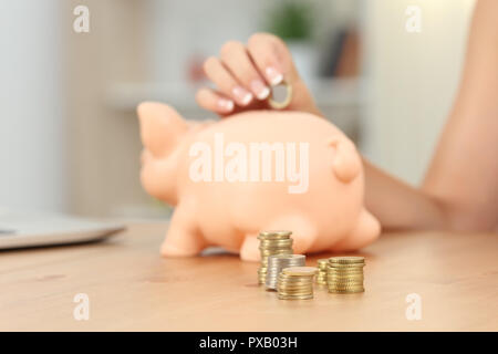 Nahaufnahme einer Frau Hand coinc in piggy Bank Stockfoto