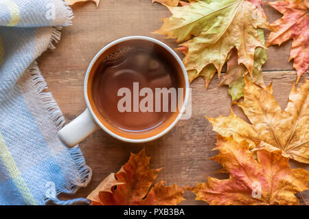 Ansicht von oben orange Kaffee Tasse im Rahmen der Herbst farbige Ahorn Blätter auf den braunen Holz- Hintergrund aus Brettern. Stockfoto