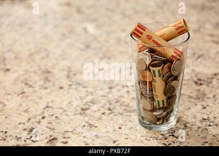 Glas Glas von Münzen in Schale am Schreibtisch Geld zu sparen, Schulden Bank reichen Armen dollar Finanzen Wohlstand ändern Markt cash Stockfoto