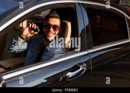 Positive junge Mann präsentiert ein neues Auto Stockfoto