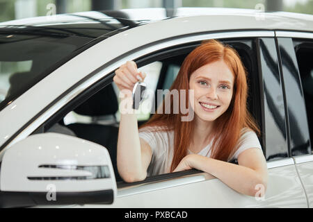 Überglücklich Treiber Frau lächelnd und zeigt neue, während Sie sich im Autohaus sitzen Stockfoto