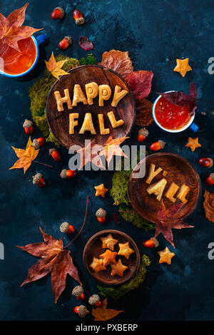 Glücklich fallen Essen Schriftzug mit Cookies. Herbst flach mit Tee, Süßigkeiten und gefallenen Blätter auf einem dunklen Hintergrund mit Kopie Raum Stockfoto