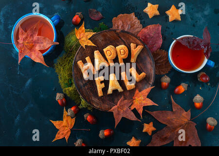Glücklich fallen Essen Schriftzug mit Cookies. Herbst flach mit Tee, Süßigkeiten und gefallenen Blätter auf einem dunklen Hintergrund mit Kopie Raum Stockfoto