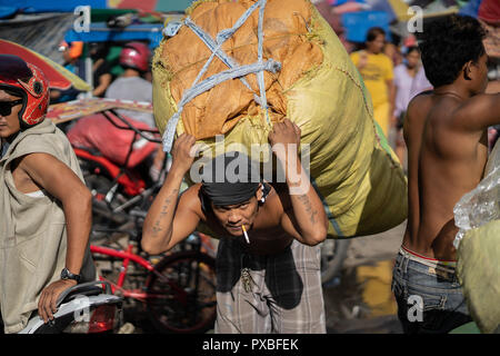 Ein Filipino Mann trägt einen großen Sack mit Güter geladen, Cebu City, Phiulippines Stockfoto