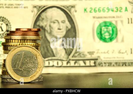 Euro Münzen von einem Dollar Banknoten als Hintergrund. Close-up von mehreren Euro Münzen. Konzept der Handel an der Börse. Wechselkurs des Euro Stockfoto