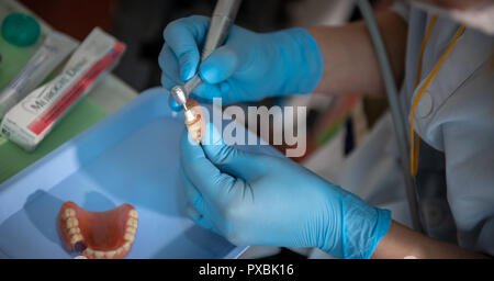 Dental Assistant manuell reinigen alten Zahnersatz von Hand Stockfoto