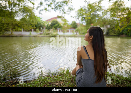 Junge schöne asiatische Frau Entspannen am See im Park
