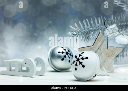 Christbaumschmuck, Holz- Stern- und Glaskugel auf grauem Hintergrund mit unscharfen Fir Tree Branch und Leuchten Stockfoto