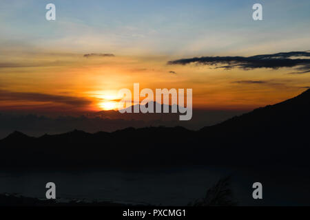 Frühen sonnenaufgang Blick von Gunung Batur Vulkan auf Bali, Indonesien mit sichtbaren Silhouette des Rinjani Berge Stockfoto