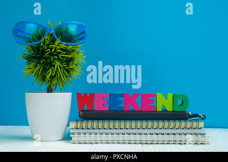 Wochenende Buchstaben text und Notebook Papier und wenig Deko Baum in weiße Vase auf hölzernen Hintergrund, hallo Wochenende Urlaub Konzept Idee. Stockfoto
