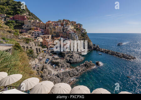 Aussichtspunkt mit Sonnenschirmen nach Manarola, Cinque Terre, Ligurien, Italien bewundern. Stockfoto