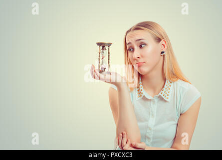 Blonde Frau, die Mitleid Gesichtsausdruck und Sanduhr in der Hoffnung. Stockfoto