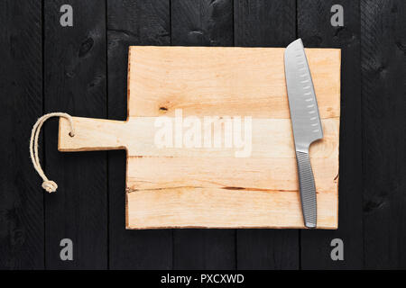 Blick von oben auf die schneidbrett mit Edelstahl Rostfrei Gemüsemesser auf schwarzem Holz- Hintergrund mit kopieren. Stockfoto