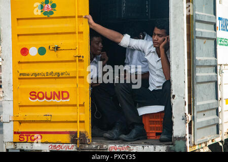 Arbeitnehmer, die in der Rückseite eines Lkw in Chennai, Indien Stockfoto