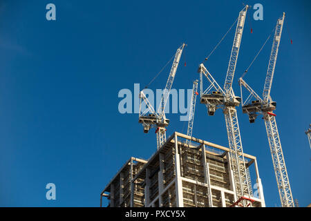 Drei weiße Kräne auf der Baustelle mit einem blauen Himmel Hintergrund Stockfoto