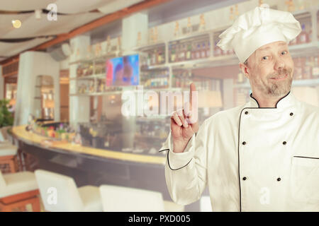 Der Koch ist ein weißer Mann in Uniform mit einer Theke. Stockfoto