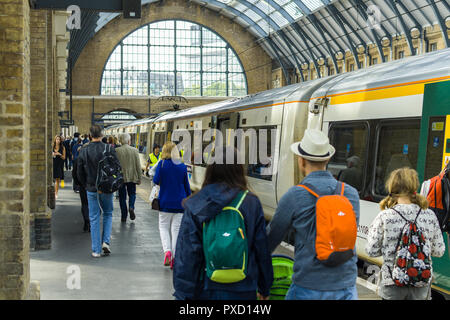 Pendler hinter einen Zug bei einer Plattform in King's Cross Station an einem sonnigen Tag Sommer, London, UK Stockfoto