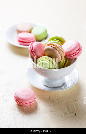 Bunte Cookies Macaron in das weiße Porzellan Tasse auf einem hellen Hintergrund Stockfoto