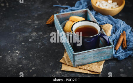 Blau emailliert Tasse Tee, Zimtstangen, Anis Sterne und Shortbread auf einem dunklen Hintergrund. Platz für Text. Stockfoto