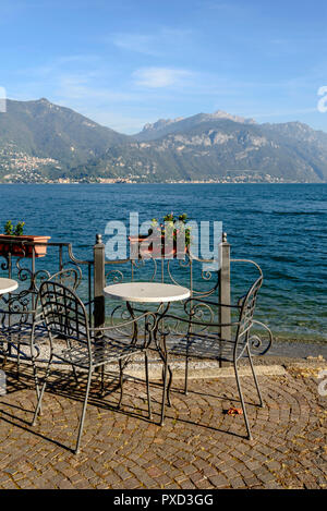 Schmiedeeiserne Stühle und Tisch auf der Seeseite der Comer see, im Hellen fällt Licht in Menaggio, Como, Italien geschossen Stockfoto