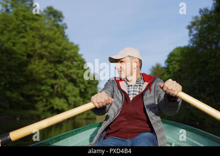 Reifer Mann in ungezwungener Kleidung auf einem Ruderboot Stockfoto