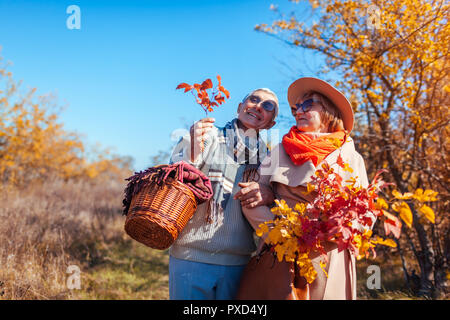 Senior Paar im Herbst Wald. Im mittleren Alter Mann und eine Frau umarmen und Chillen im Freien. Die Menschen reden und die Natur genießen Stockfoto
