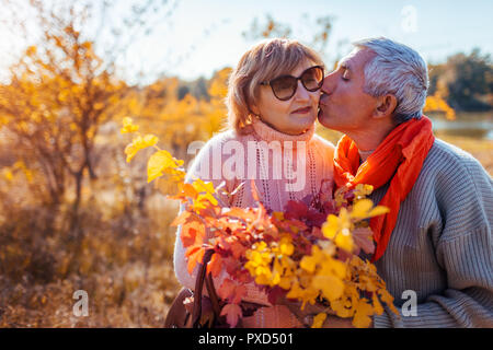Senior Paar im Herbst Wald. Mann mittleren Alters küssen und umarmen Frau. Zeit mit der Familie Stockfoto