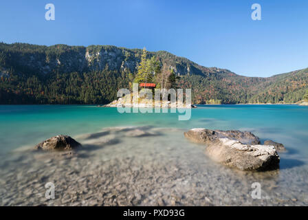 Die Steine am Ufer der Insel Braxeninsel vor der Schönbichl Insel im Eibsee bis Herbst Wald, Bayern umgeben, Deutschland Stockfoto