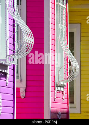 Fragment einer mehrfarbigen Fassade des Hauses mit gebogenen Stangen an den Fenstern. Stockfoto