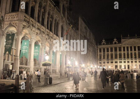 Blick auf den Grande Place, in Brüssel, Belgien bei Nacht. Elegante gotische Gebäude säumen den historischen Platz, wenn die Touristen vorbeikommen. Stockfoto