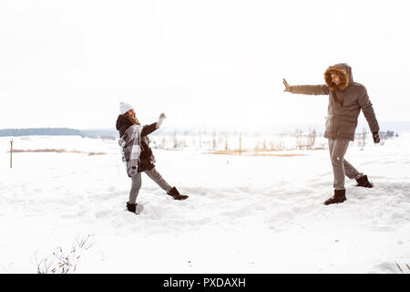 Sorglos glückliches junges Paar gemeinsam Spaß im Schnee im Winter woodland das Werfen mit Schneebällen an jedem anderen während eines mock kämpfen. Stockfoto