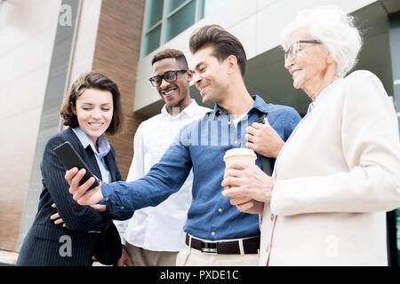 Freundliche Kollegen über praktische mobile App für Unternehmen Stockfoto