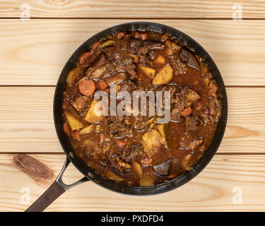 In der Nähe der bunten Ziege Eintopf im Kochen pan auf Holztisch. Stockfoto