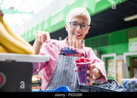 Portrait der älteren Frau verkauft Himbeeren auf dem Markt Stockfoto