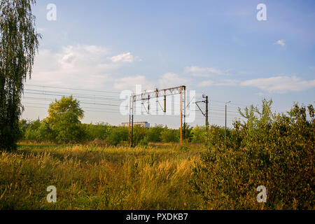 Elektrische Türme über Bahngleise in Großpolen auf den warmen sonnigen Tag mit wilden Vegetation rund um Stockfoto