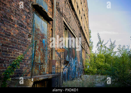 Alten Bahnhof Fabrik Ruinen mit industriellen Mauerwerk und großen blauen Türen an einem warmen sonnigen Tag bringen nostalgische Gefühle Stockfoto