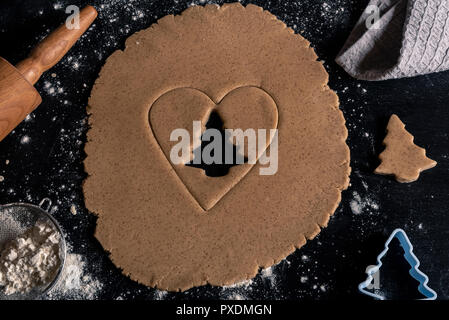Oben Ansicht mit weihnachtsbäckerei Tisch, Lebkuchen Teig mit einem Herz und Baum geschnitten von es Stockfoto