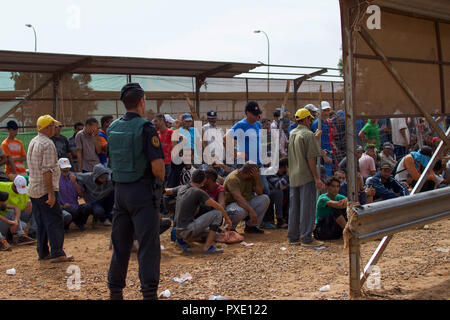 Ceuta, Melilla, Spanien. 13 Aug, 2018. Offiziere mit der spanischen Guardia Civil watch Als marokkanische Arbeiter für ihre Umdrehung warten Pakete über die Grenze nach Marokko. Die Spanische Enklave Stadt Melilla liegt an der nordafrikanischen Küste, von allen Seiten von Marokko und das Mittelmeer umgeben. Die Stadt wird von einer 20 m hohen Metallzaun heraus zu halten Migranten auf der Suche nach Europa zu kommen, umgeben, aber viele Migranten machen es auf jeden Fall. Die Grenze ist aber auch eine blühende wirtschaftliche Drehscheibe, wo marokkanische Arbeiter waren aus Spanien in Marokko. (Bild: © SOPA Bilder über ZUMA Stockfoto