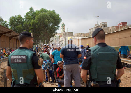 Ceuta, Melilla, Spanien. 13 Aug, 2018. Marokkaner sind gesehen Futter bis zu 10 Euro mit einem 50 kg Paket von gebrauchter Kleidung und andere Waren erwerben melila über die Grenze nach Marokko. Die spanische Exklave Melilla Stadt an der nordafrikanischen Küste sitzt, von allen Seiten von Marokko und das Mittelmeer umgeben. Die Stadt wird von einer 20 m hohen Metallzaun heraus zu halten Migranten auf der Suche nach Europa zu kommen, umgeben, aber viele Migranten machen es auf jeden Fall. Die Grenze ist aber auch eine blühende wirtschaftliche Drehscheibe, wo marokkanische Arbeiter waren aus Spanien in Marokko. (Bild: © SOPA I Stockfoto