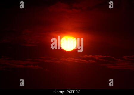 Die Sonne Filterung durch die silhouetting Wolken. Stockfoto