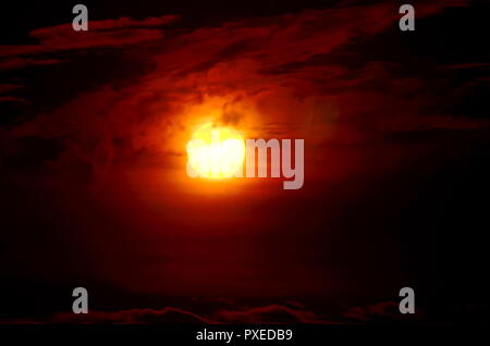 Die Sonne Filterung durch die silhouetting Wolken. Stockfoto