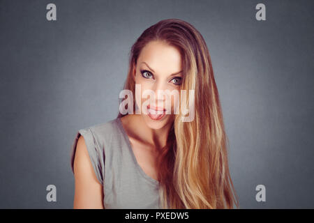 Emotionale Mädchen. Schöne moderne Modell Mädchen, Frau zeigt die Zunge auf Grau Grau studio Wand horizontal Hintergrund isoliert. Positive Gesichtsausdruck. E Stockfoto