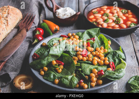 Kichererbsen und Gemüse Salat mit Spinat Blätter, gesund Hausgemachte veganes Essen, Diät. weiße Bohnen in Tomatensoße Stockfoto