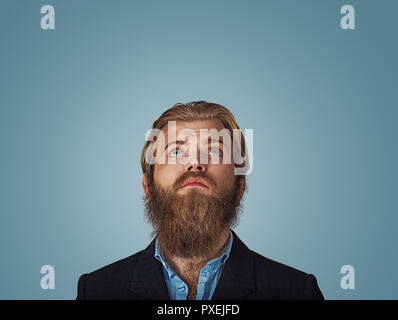 Kopf geschossen ernste Hipster business Mann denken, blickte nachdenklich auf Grau graue Wand Hintergrund mit Kopie Raum über dem Kopf isoliert verwirrt. Menschliche Stockfoto