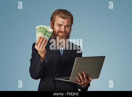 Erfolgreiche lächelnden jungen Mann mit Laptop Gebäude online Business Geld verdienen euro Rechnungen in Bar. Anfänger es Unternehmer Erfolg wirtschaft Konzept. Stockfoto